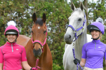 Two riders with horses wearing headcollars