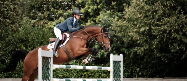 Rider wearing a competition jacket as she rides on a horse