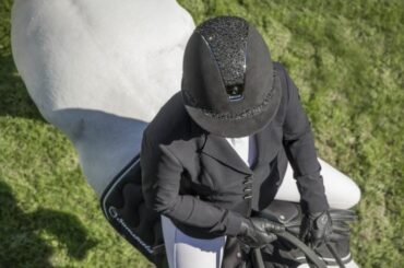 A rider wearing a Samshield riding hat riding a white horse