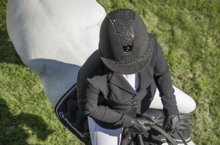 A rider wearing a Samshield riding hat riding a white horse